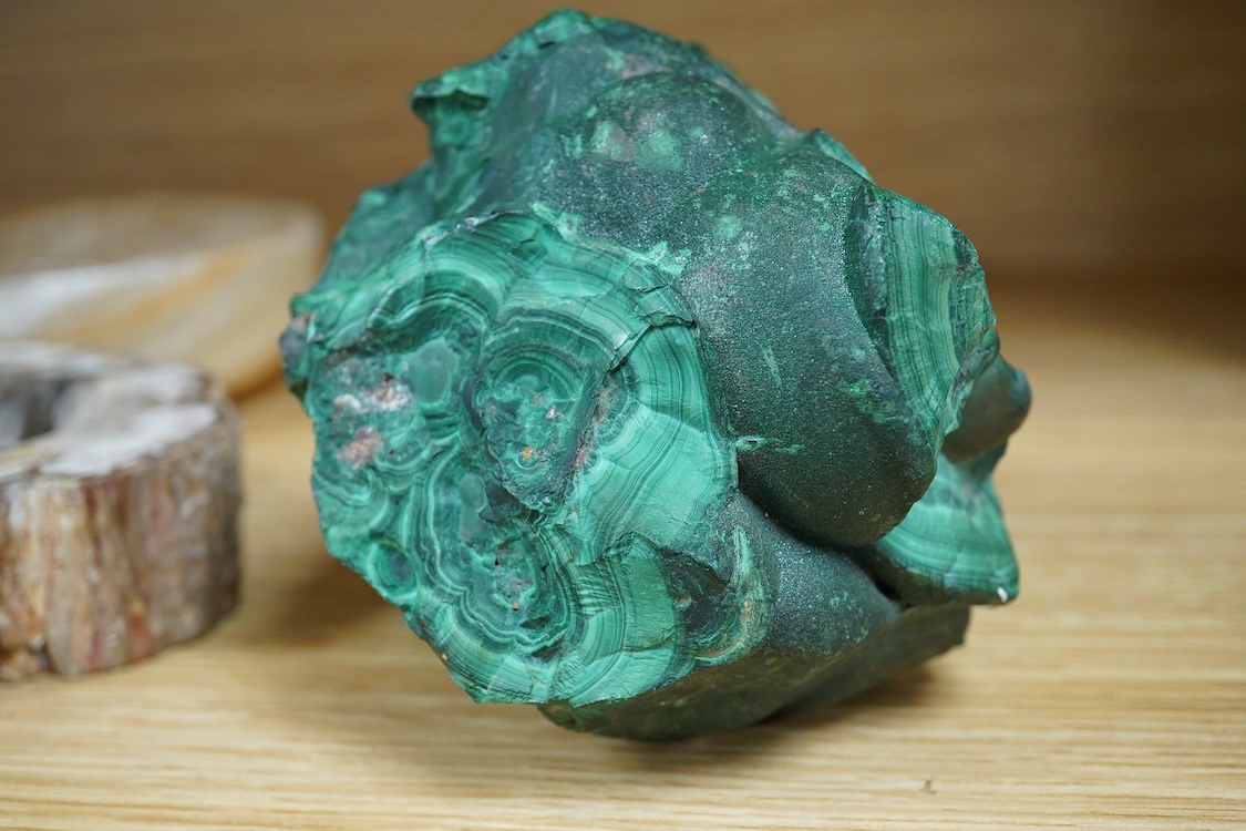 Two petrified wood ashtrays, a malachite rock, three onyx bowls, one with cover, and one other item, larger ashtray 17.5cm wide